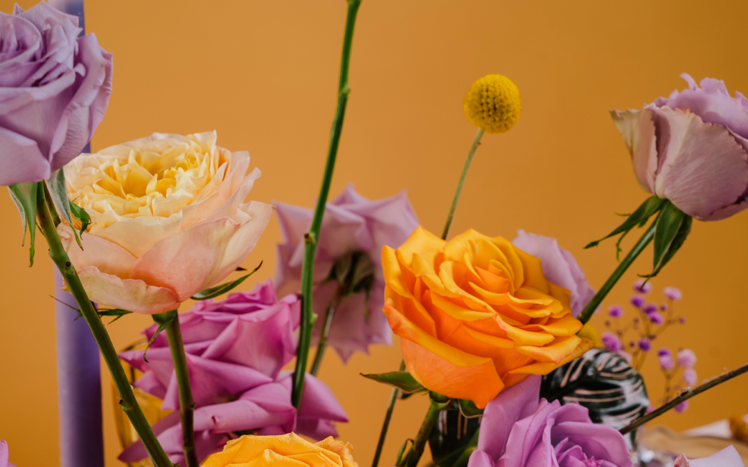 A close-up of purple, orange, and yellow roses set against a golden background.
